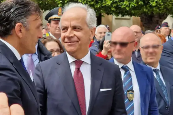 Uomini in abito scuro e cravatta, uno sorride. Dietro, un uomo con cappello da ufficiale. Forse un evento che illustra come si diventa prefetto.