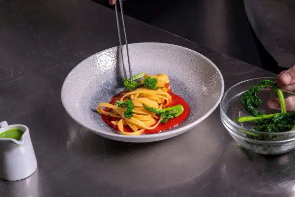 Impiattamento di pasta con broccoli e salsa rossa. La cura nei dettagli mostra come si diventa chef.