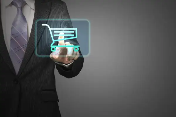 Un uomo in giacca e cravatta preme un carrello della spesa virtuale, mostrando cosa fa un buyer nell'era digitale.