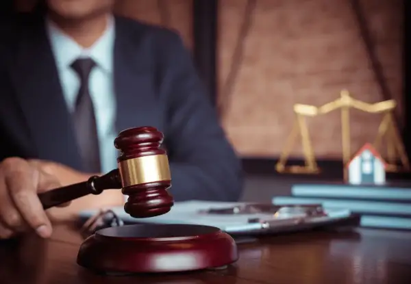 Giudice con martelletto, bilancia della giustizia e casa in miniatura. Un futuro master criminologia pegaso potrebbe studiare questo caso.