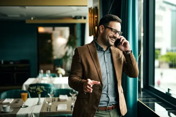 Un uomo sorride al telefono, un esempio di come un **innovation manager cosa fa**: gestisce idee e progetti con entusiasmo, in un ambiente moderno.