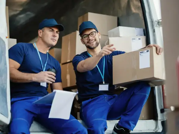 Due fattorini discutono di un pacco, forse valutando il loro stipendio da supply chain manager.