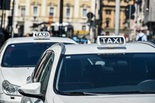 Tassisti in attesa, chissà quanto guadagna un tassista in questa città. Auto bianche con insegna TAXI.