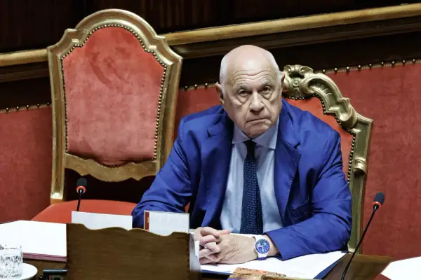 Uomo con completo blu e cravatta, seduto in un'aula istituzionale. Un esempio di chi ha deciso di diventare magistrato a 50 anni, con determinazione.