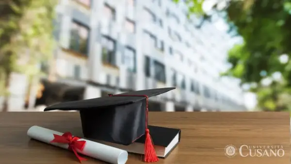 Cappello da laureato, pergamena e libro su un tavolo di legno. Unicusano riconosciuta dal MIUR, simbolo di successo accademico.