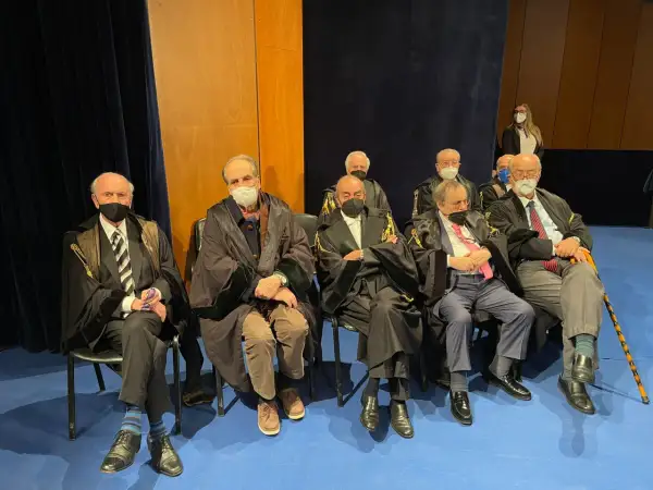 Uomini in toga seduti, alcuni con mascherina. Un uomo anziano potrebbe diventare avvocato a 50 anni, dimostrando che non è mai troppo tardi.