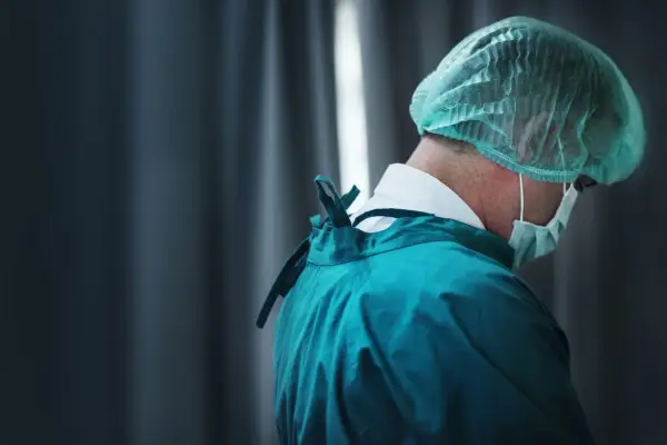 Professionista sanitario in camice verde e cuffia, con mascherina. Cerca offerte lavoro OSS per un futuro nel settore.